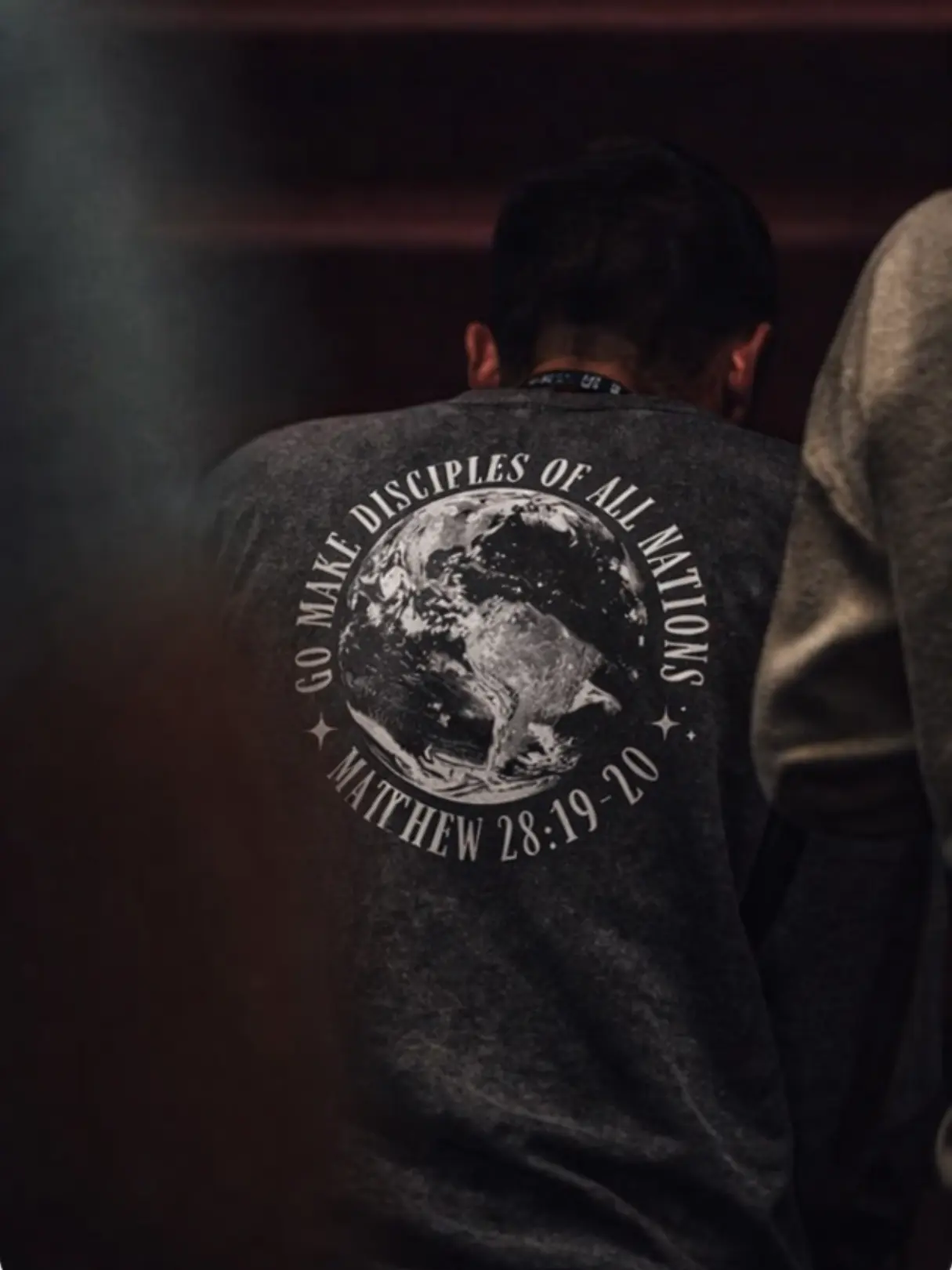 Back view of a black Christian T-shirt featuring a globe design with “Go Make Disciples of All Nations – Matthew 28:19-20”